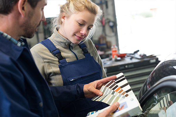 An image of a happy woman talking to a mechanic about her options for her car