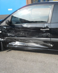 Image of a black car with a dent and scrapes along the side