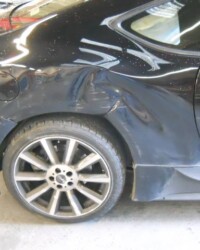 An image of a black car with a massive dent